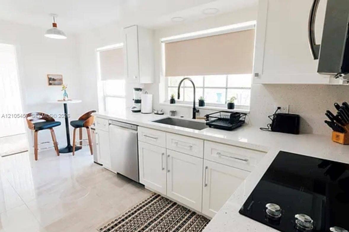 1083 SW 25th Avenue, Boynton Beach, FL 33426 Kitchen featuring white cabinetry, solid-surface countertops, a stainless steel dishwasher, a recessed sink with a matte black faucet, and a black electric cooktop