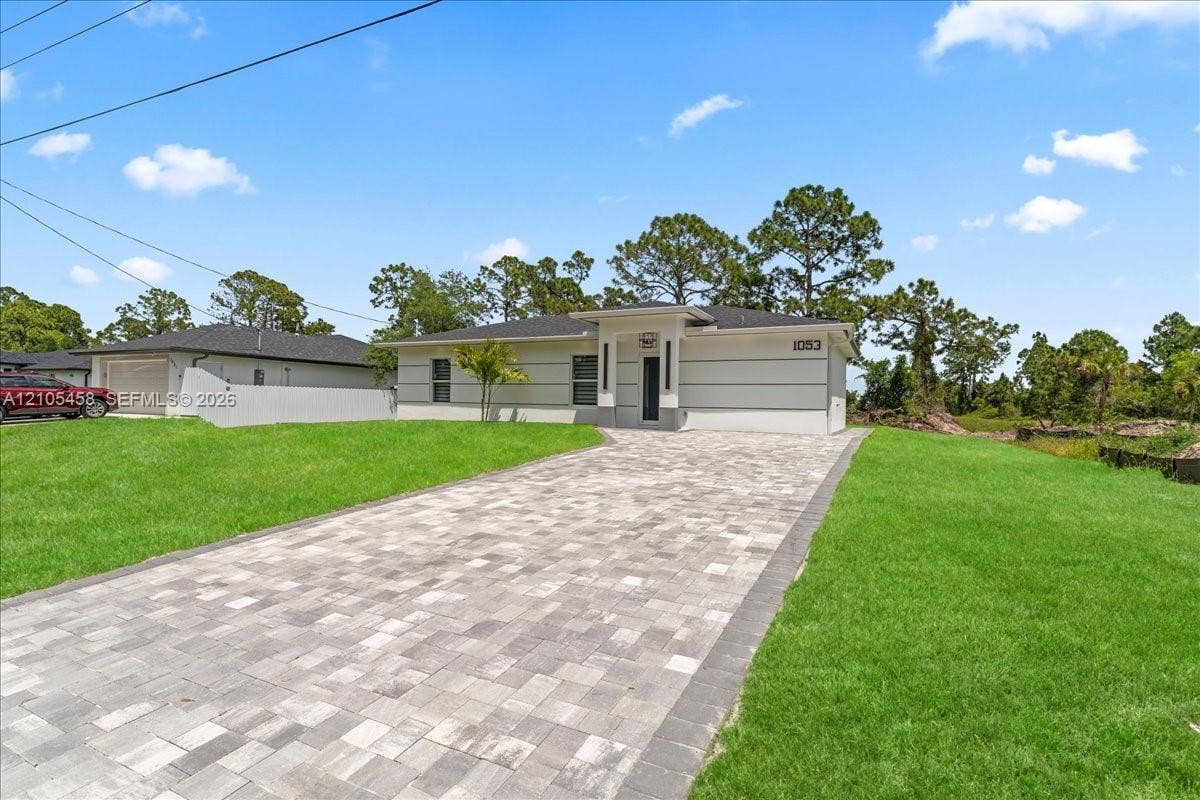 Modern-style exterior with gray siding, white trim, and a paver driveway