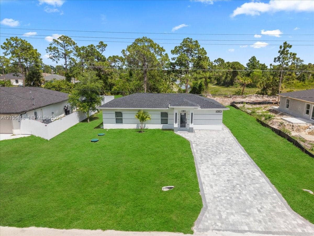 Contemporary single-story exterior with white siding, dark shingle roof, and paver driveway