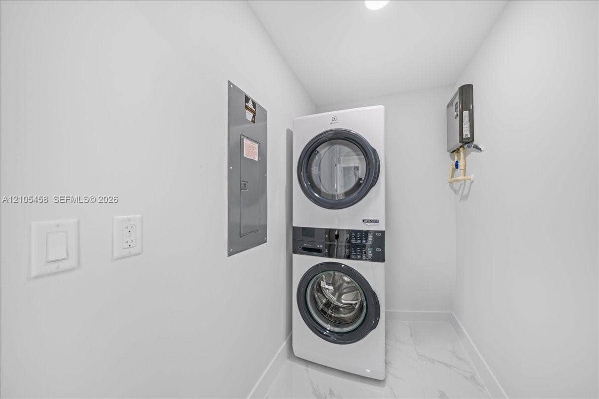 Stacked laundry appliances with a front-loading washer and dryer, recessed lighting, and large format floor tiling