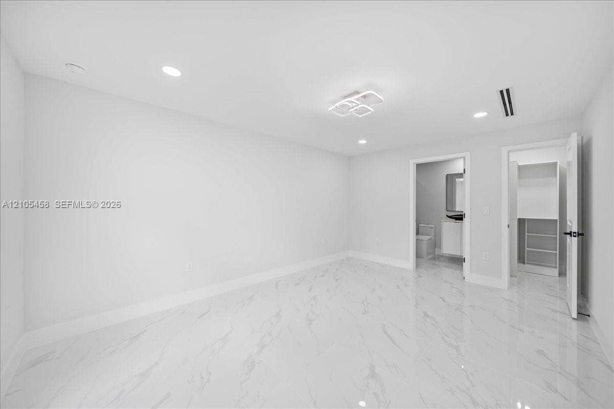 Recessed lighting, contemporary ceiling fixture, polished tile flooring, built-in closet shelving, and a white vanity with a rectangular mirror