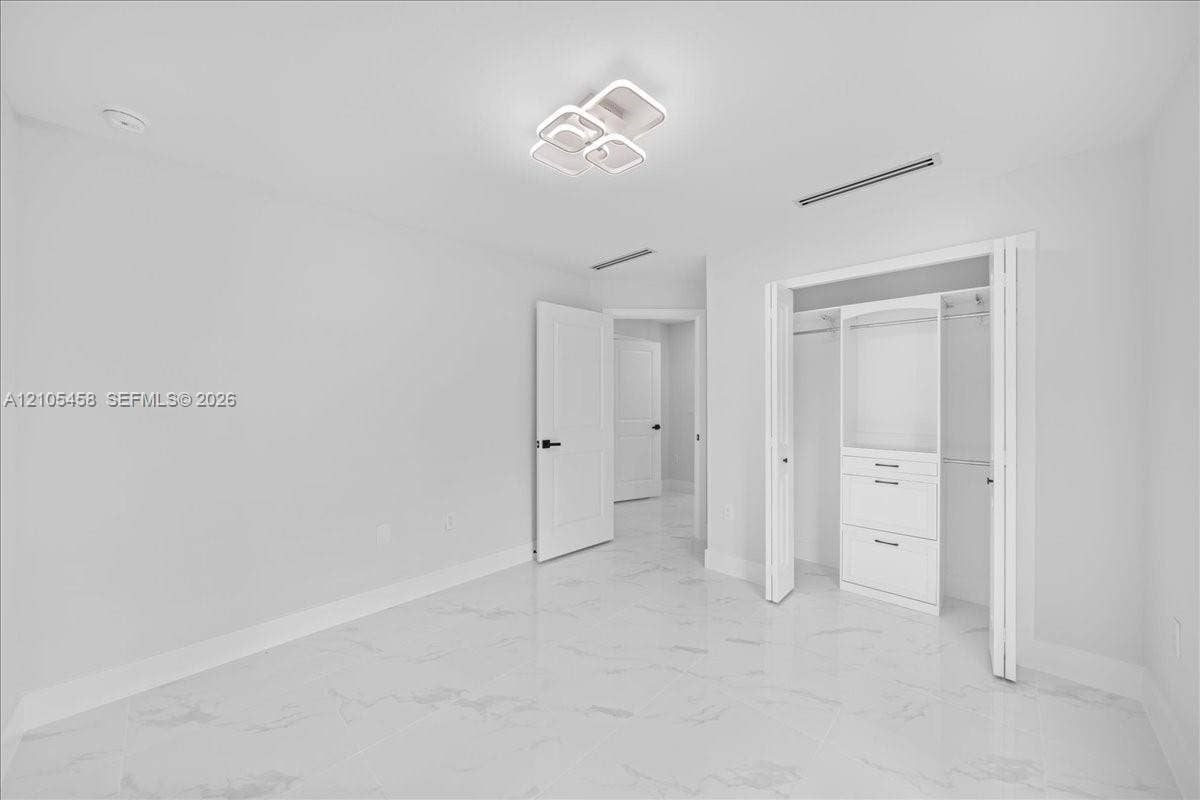 White tile flooring, contemporary ceiling light fixture, white interior doors, built-in closet organization system, recessed lighting