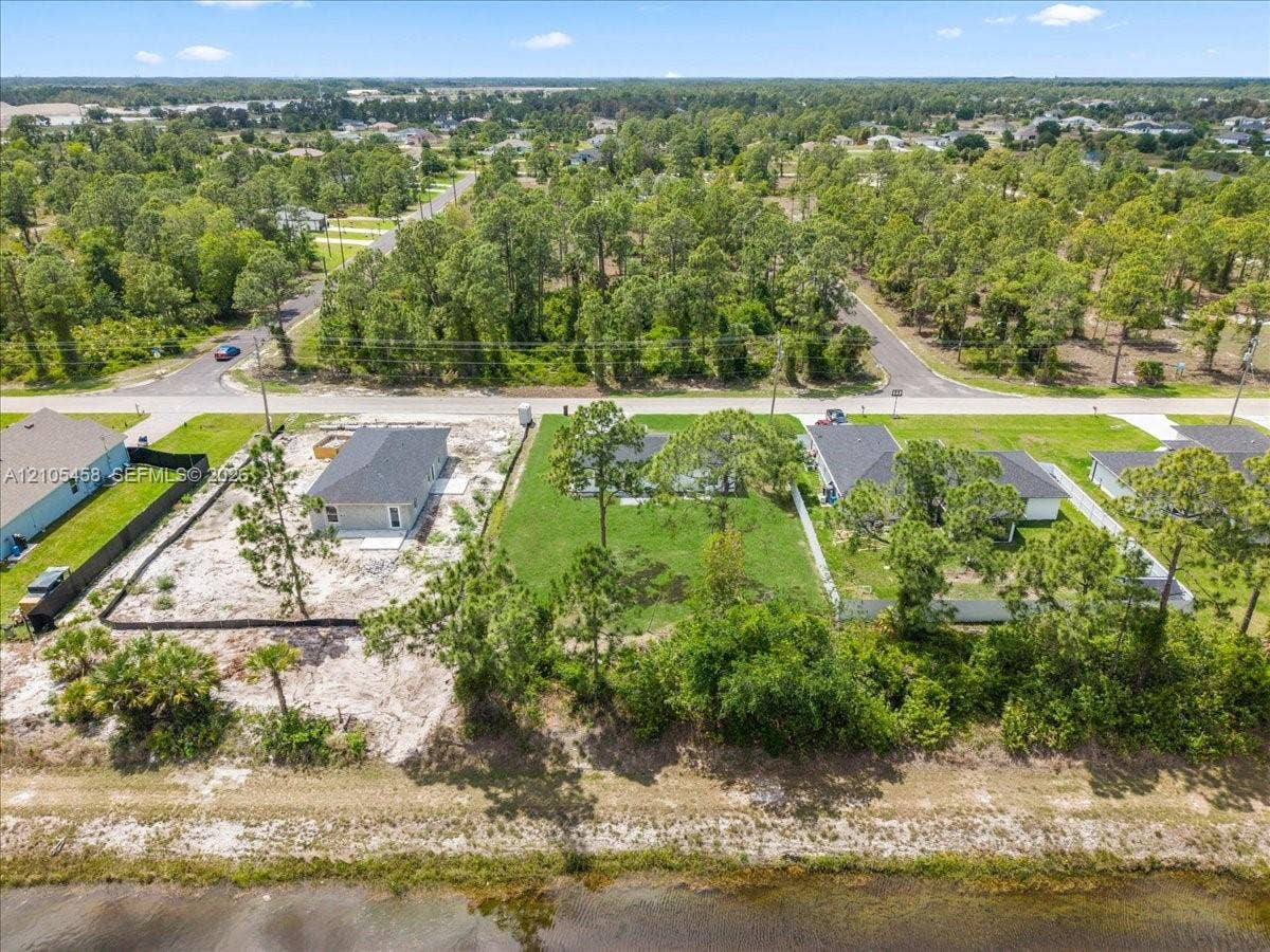 Expansive lot with partial land clearing, partially wooded surroundings, and a water frontage
