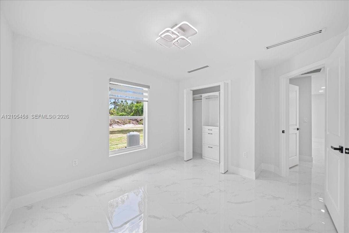 White tile flooring, modern ceiling light fixture, built-in closet storage, window with privacy blind, white panel doors