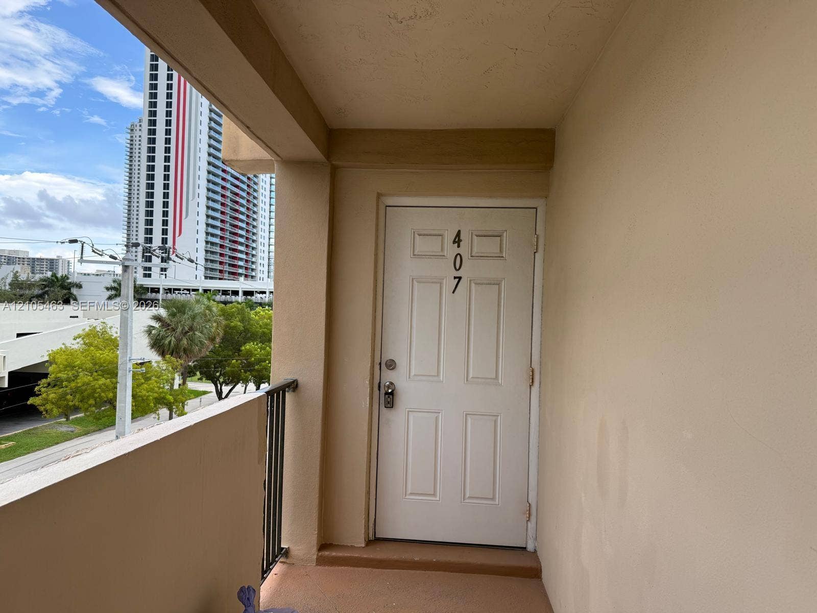 Balcony entrance with a paneled door, black metal railing, and a painted concrete floor