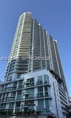 High-rise residential building featuring multiple balconies, a curved facade, and a multi-level base structure