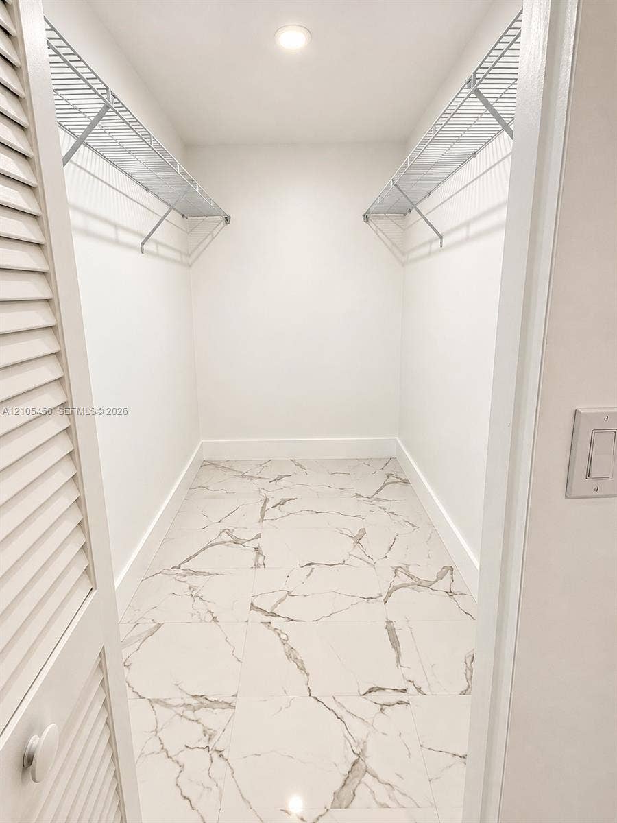 5300 Washington Street, #I201, Hollywood, FL 33021 Recessed ceiling light, white walls, wire shelving, marble-look floor tiles, and louvered bifold doors
