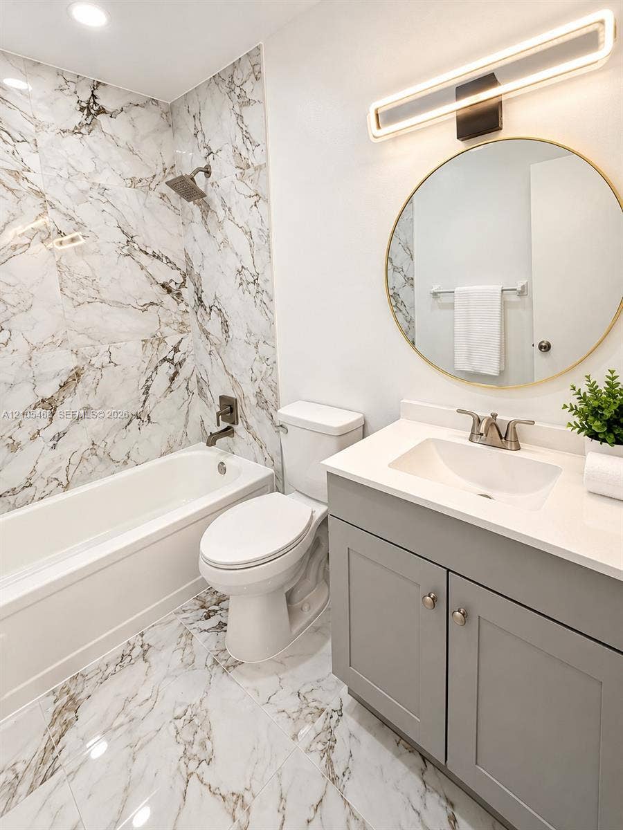 5300 Washington Street, #I201, Hollywood, FL 33021 Bathroom with full bathtub, matching marble-look floor and shower surround, and a gray vanity with an integrated sink and light-colored countertop