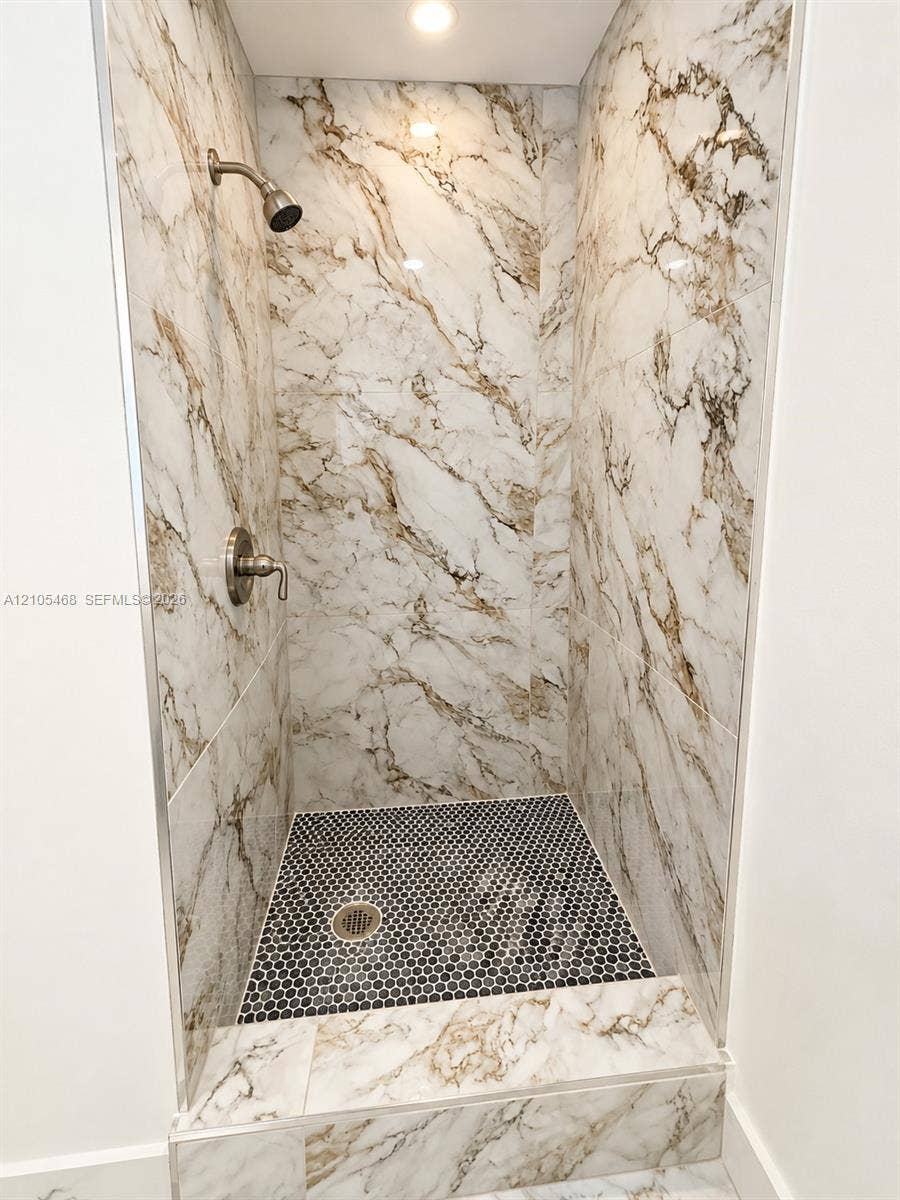 5300 Washington Street, #I201, Hollywood, FL 33021 Walk-in shower featuring large format wall tiles with prominent veining, a mosaic tile shower pan, and a recessed ceiling light