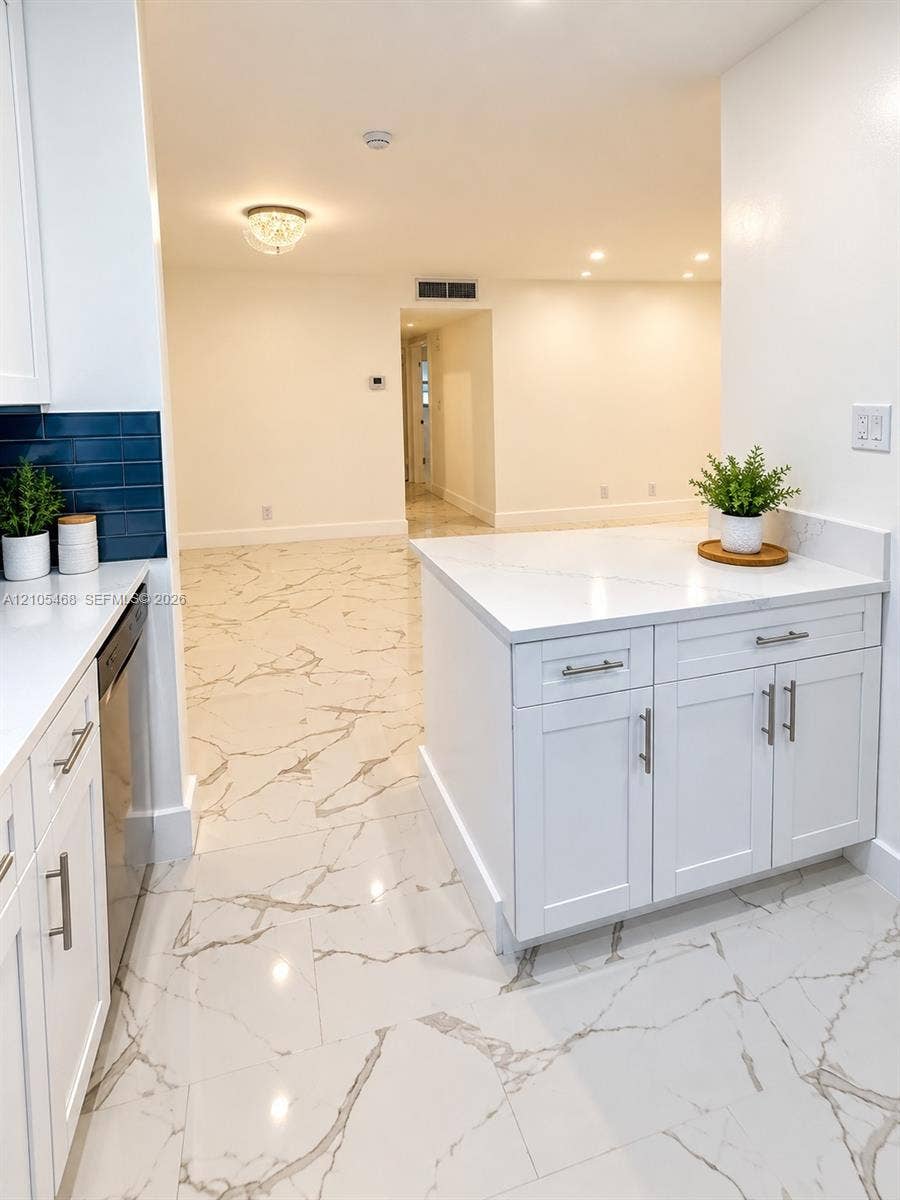 5300 Washington Street, #I201, Hollywood, FL 33021 White shaker cabinetry, patterned tile flooring, blue subway tile backsplash, recessed lighting, and a kitchen island with stone countertop