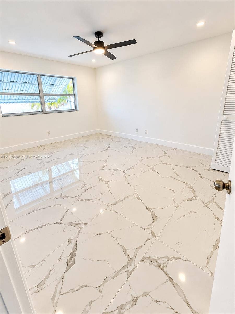 5300 Washington Street, #I201, Hollywood, FL 33021 White tile flooring with grey veining, a black ceiling fan with integrated lighting, recessed lighting, and a window with horizontal blinds