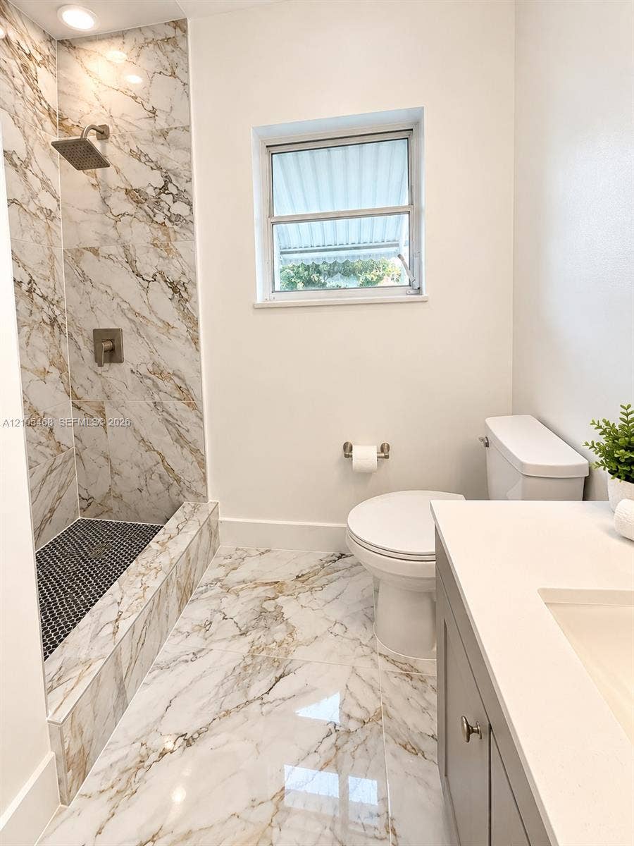 5300 Washington Street, #I201, Hollywood, FL 33021 Walk-in shower with large-format marbled tile, recessed lighting, and a black mosaic tile shower floor