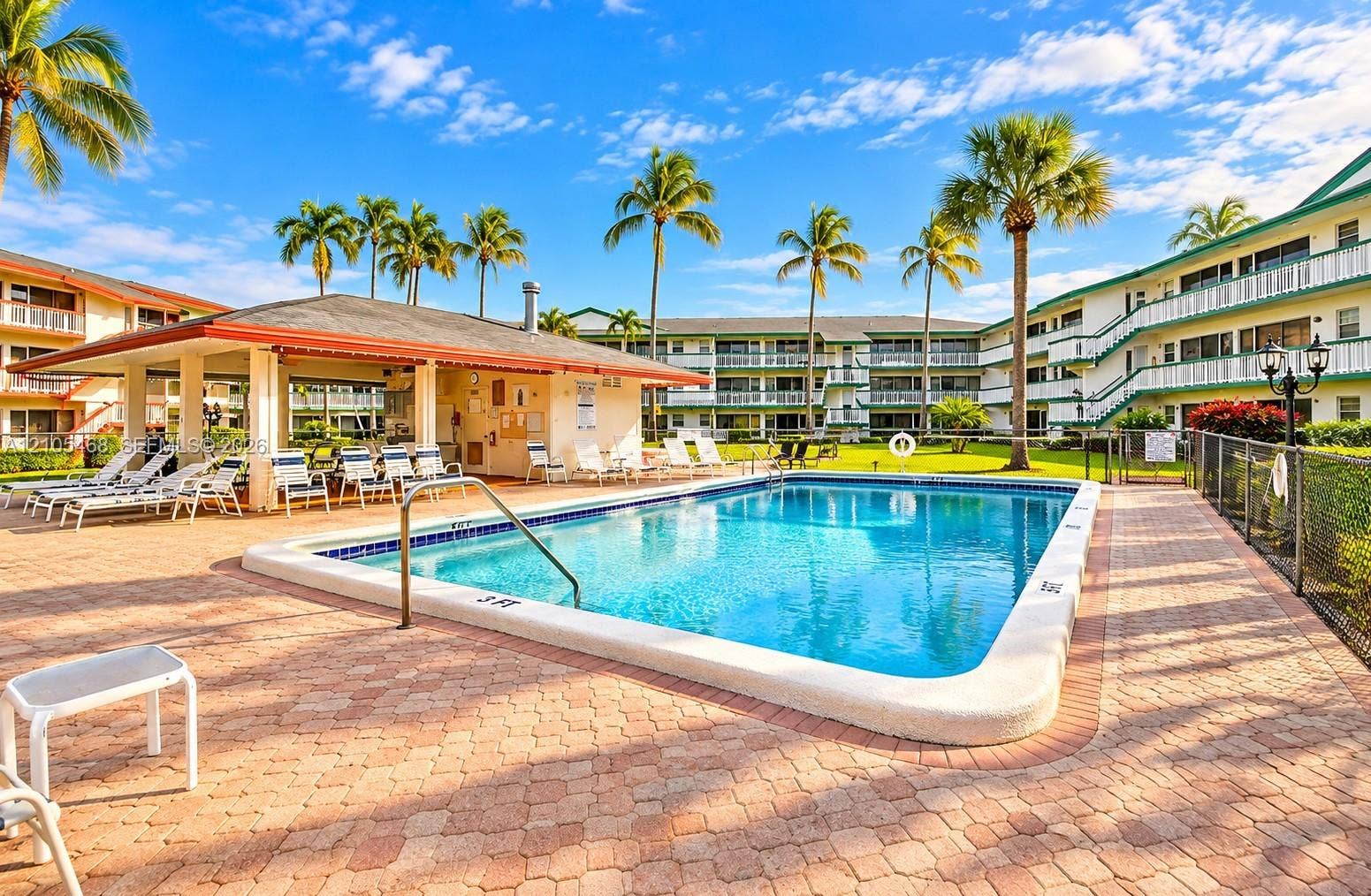 5300 Washington Street, #I201, Hollywood, FL 33021 Rectangular swimming pool with a paved deck, surrounded by palm trees and lush landscaping
