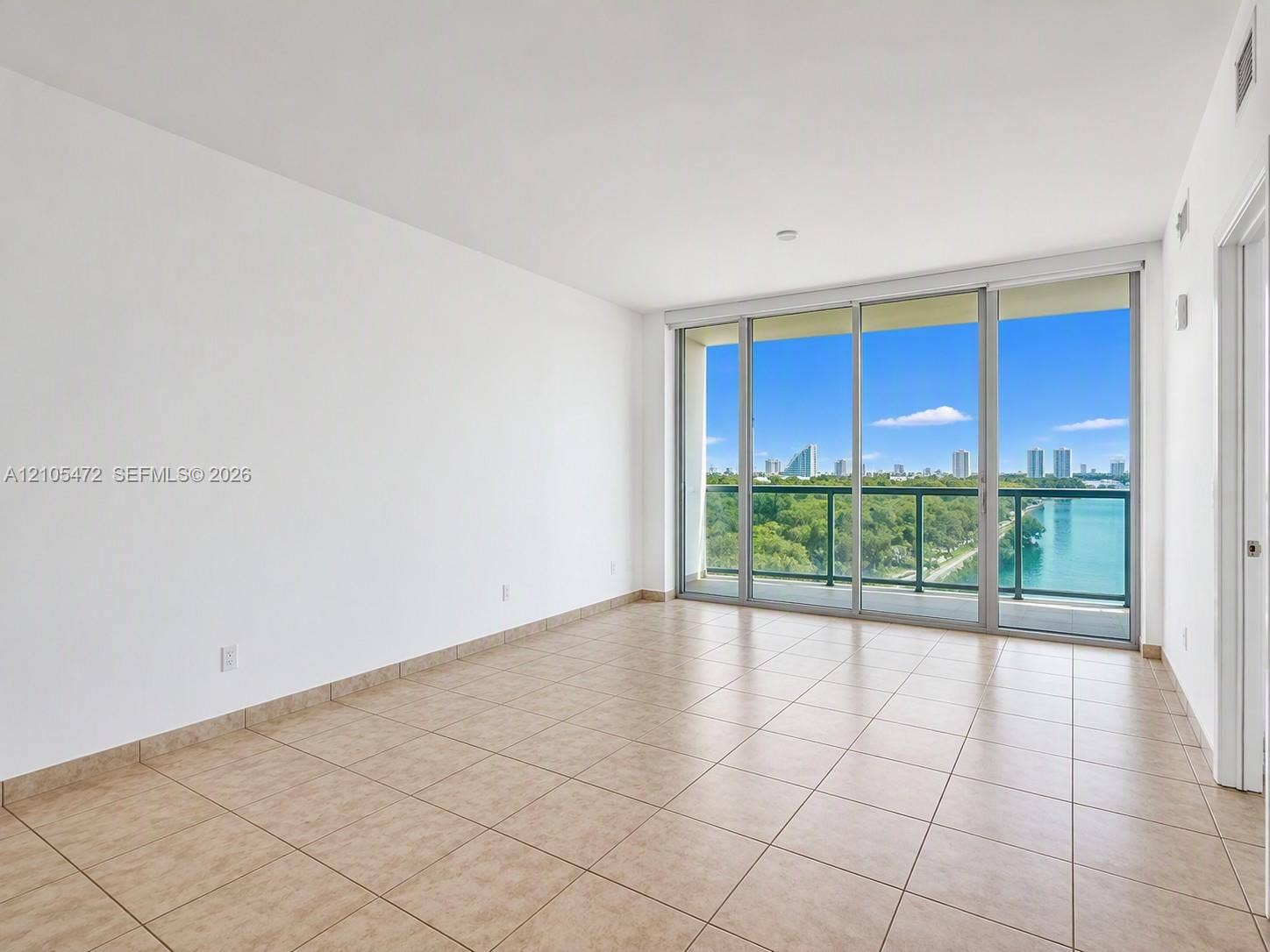 888 Biscayne Boulevard, #811, Miami, FL 33132 Neutral-toned tile flooring, floor-to-ceiling sliding glass doors, and a glass-paneled balcony featuring water and cityscape scenery