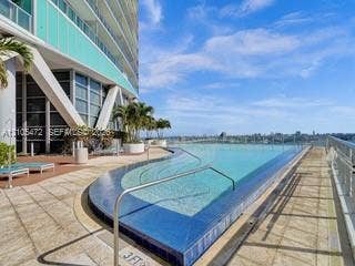 888 Biscayne Boulevard, #811, Miami, FL 33132 Infinity-edge pool with blue mosaic tile, surrounding paved decking, and integrated handrails