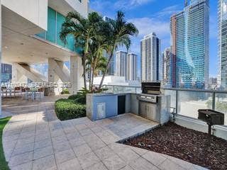 888 Biscayne Boulevard, #811, Miami, FL 33132 Outdoor entertaining area featuring a built-in grill station, tile patio, and established landscaping