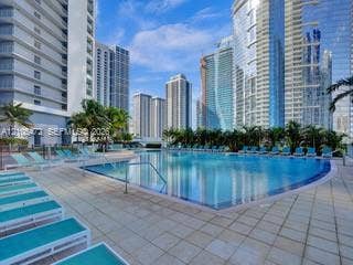 888 Biscayne Boulevard, #811, Miami, FL 33132 Expansive pool deck with a curved swimming pool, surrounded by paver tile flooring, and mature palm trees