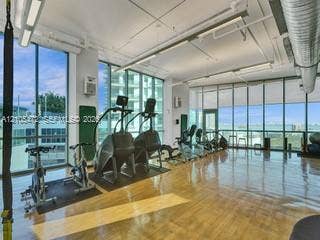 888 Biscayne Boulevard, #811, Miami, FL 33132 Expansive room with wood-finish flooring, floor-to-ceiling windows, roller shades, exposed overhead ductwork, and track lighting