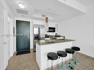 888 Biscayne Boulevard, #811, Miami, FL 33132 Kitchen featuring a peninsula island, stainless steel refrigerator, built-in microwave, and tile flooring