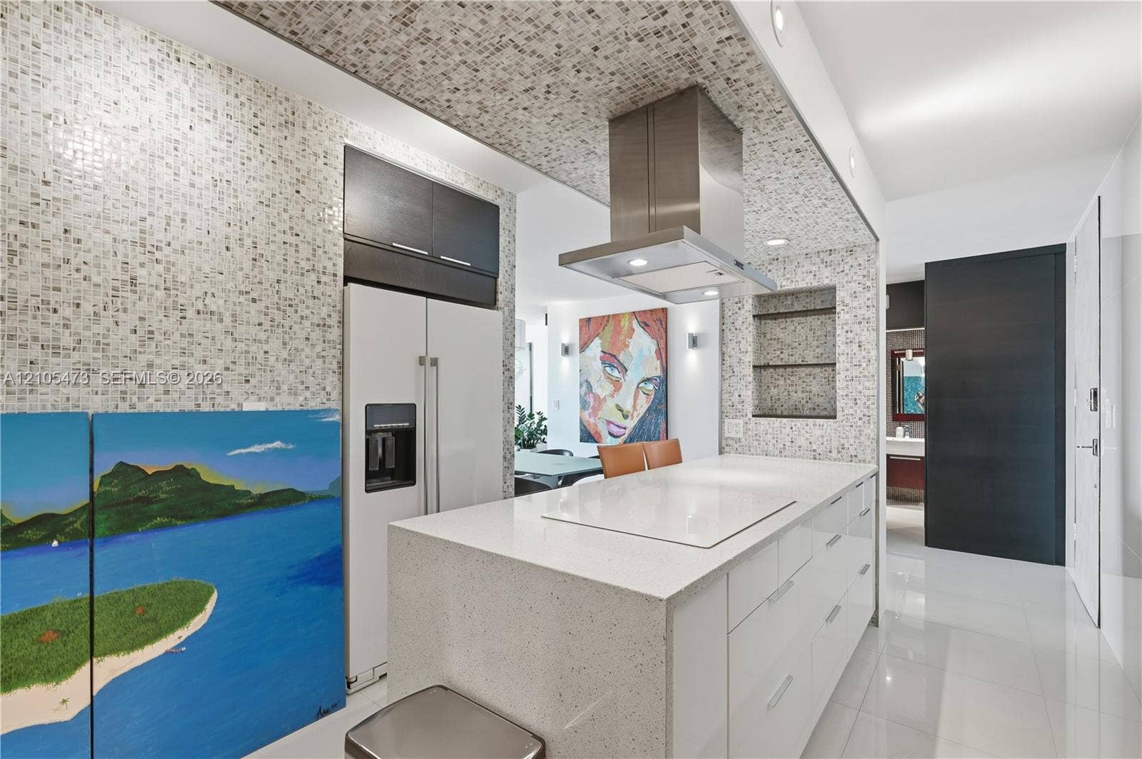 770 NE 69th Street, #6F, Miami, FL 33138 Gourmet kitchen with a large central island, white cabinetry, stainless steel range hood, and mosaic tile backsplash and ceiling accent