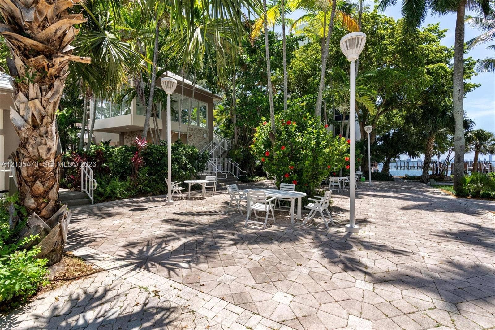 770 NE 69th Street, #6F, Miami, FL 33138 Extensive paved patio featuring geometric stone-paver hardscaping, mature palm trees, integrated post lighting, and direct access to coastal grounds