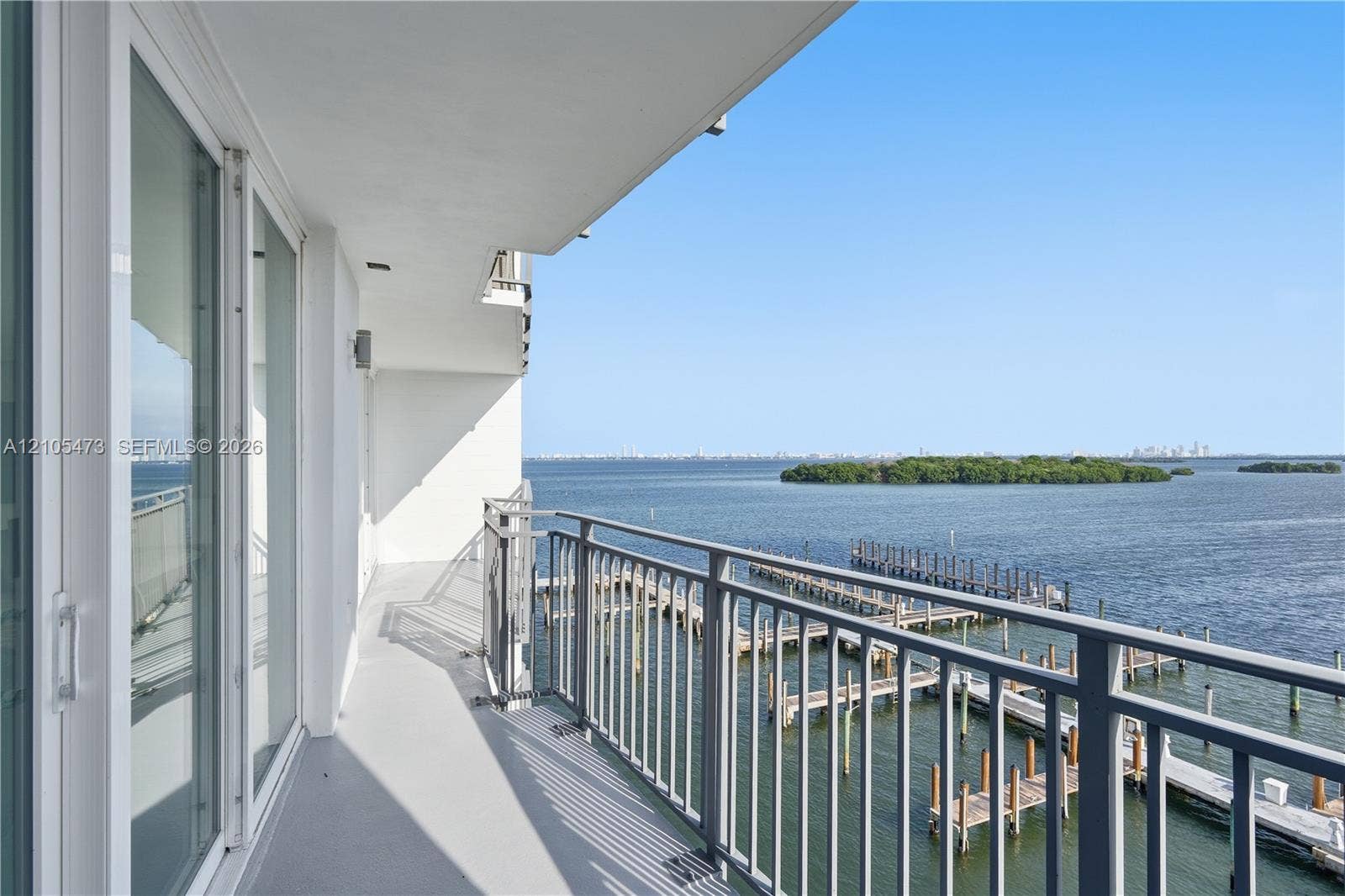 770 NE 69th Street, #6F, Miami, FL 33138 Expansive balcony featuring a metal railing system, sliding glass doors, and a water backdrop with islands and a distant cityscape