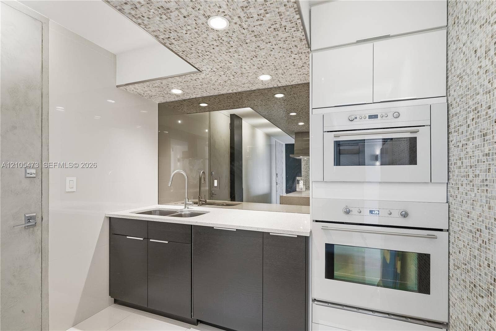 770 NE 69th Street, #6F, Miami, FL 33138 Integrated wall oven and microwave with sleek white cabinetry, mosaic tile accent wall, and recessed lighting