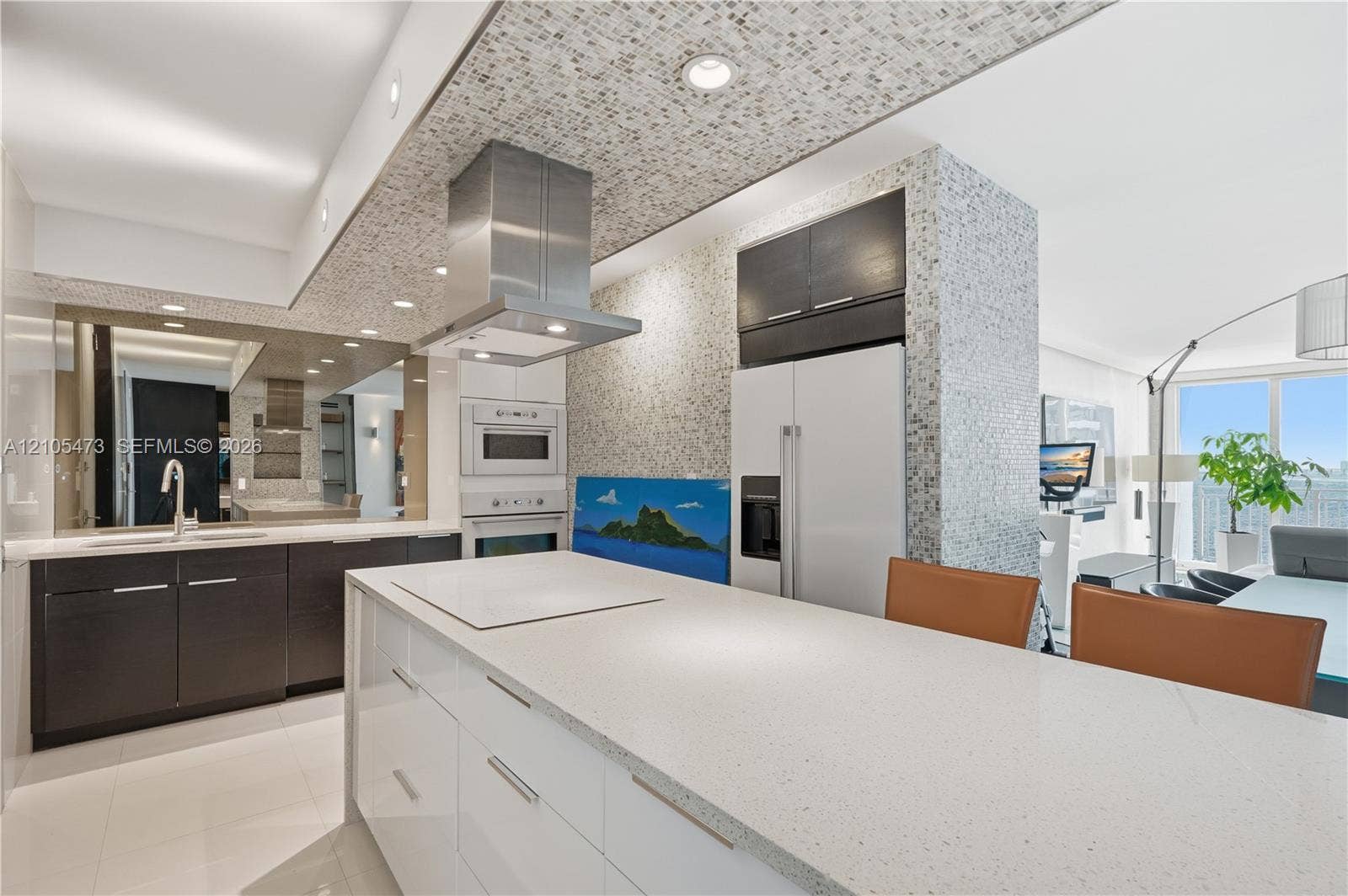770 NE 69th Street, #6F, Miami, FL 33138 Kitchen featuring a central island with an integrated cooktop, white countertop, dark wood-finish cabinetry, stainless steel range hood, and integrated wall oven