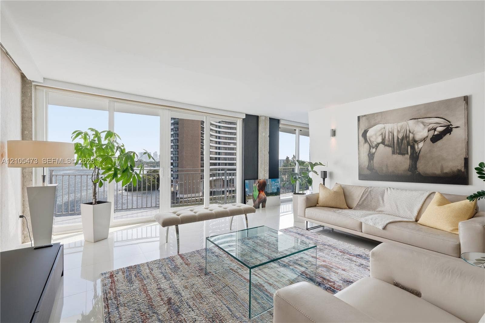 770 NE 69th Street, #6F, Miami, FL 33138 White high-gloss flooring, extensive sliding glass doors, balcony access, recessed lighting, and wall-mounted sconces