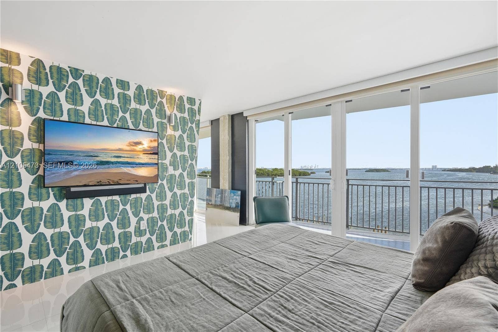 770 NE 69th Street, #6F, Miami, FL 33138 Floor-to-ceiling sliding glass doors, balcony with metal railing, water scenery, wall-mounted television, and decorative wall covering