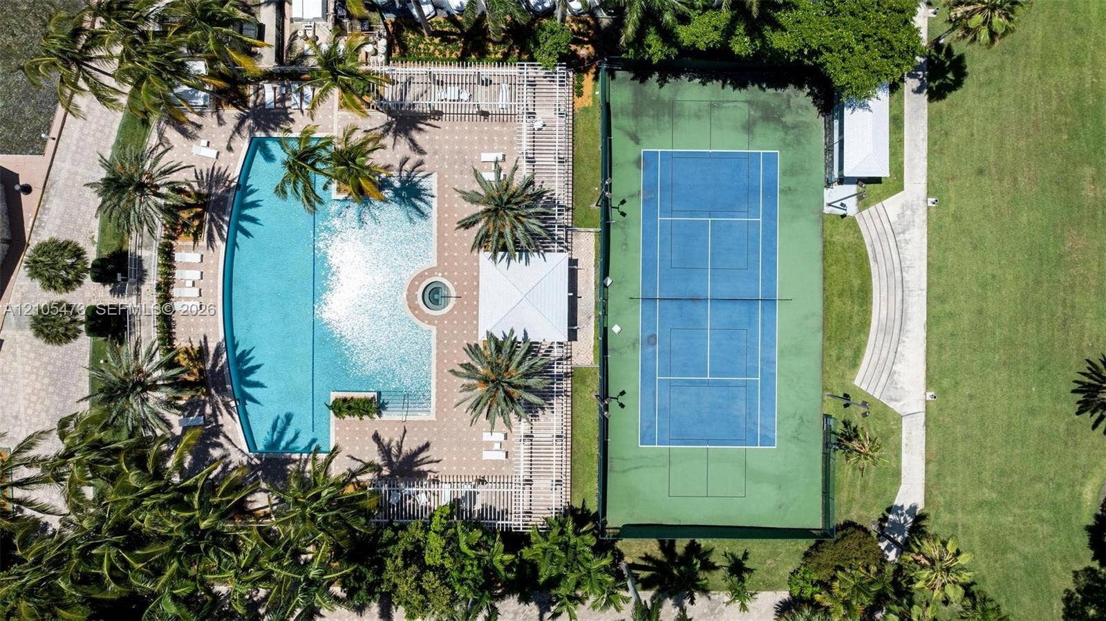 770 NE 69th Street, #6F, Miami, FL 33138 Recreational area featuring a curvilinear swimming pool with an integrated spa, a paved deck, a hard-court tennis surface, and expansive lawn space