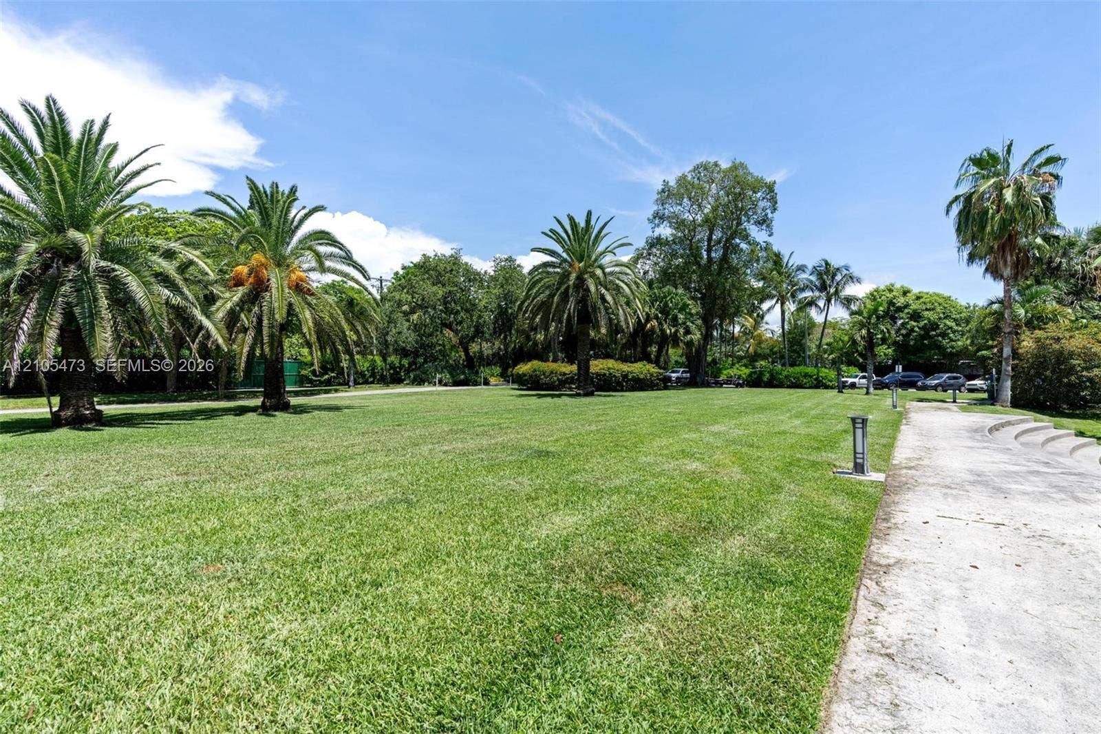 770 NE 69th Street, #6F, Miami, FL 33138 Expansive landscaped lawn featuring mature palm trees, established shade trees, and a concrete pathway with integrated lighting