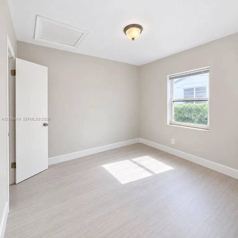 Light wood-finish flooring with white trim, neutral wall paint, and a semi-flush mount ceiling light