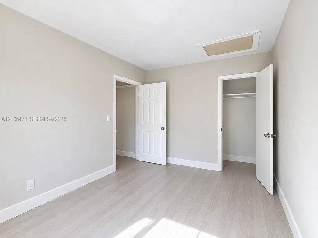 Light wood-finish flooring, neutral wall tones, white trim, and a ceiling access panel