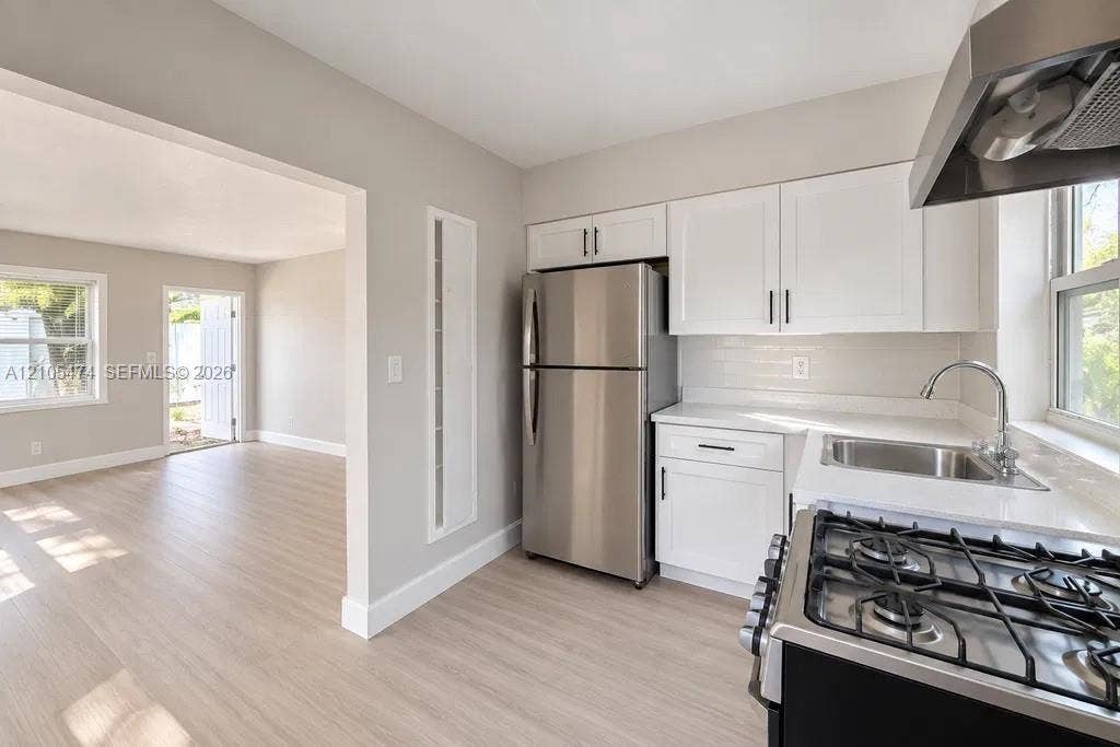 Kitchen featuring white cabinetry, stainless steel appliances, white subway tile backsplash, and light-toned countertops