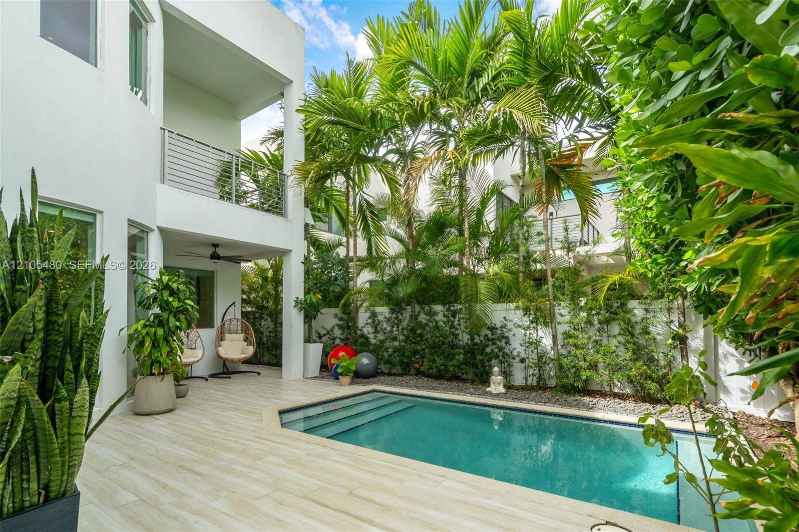 Modern white exterior with a private swimming pool featuring integrated steps, surrounded by light-toned patio pavers