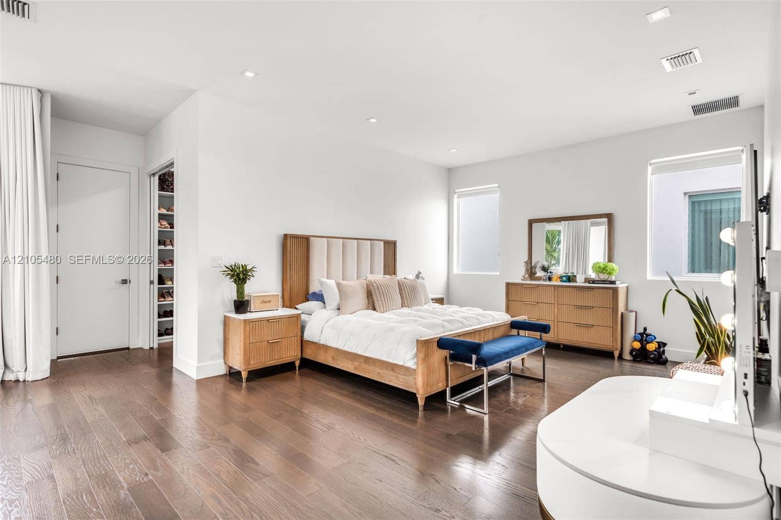 Dark wood-finish flooring, recessed lighting, white walls, multiple windows, and a built-in closet with shelving