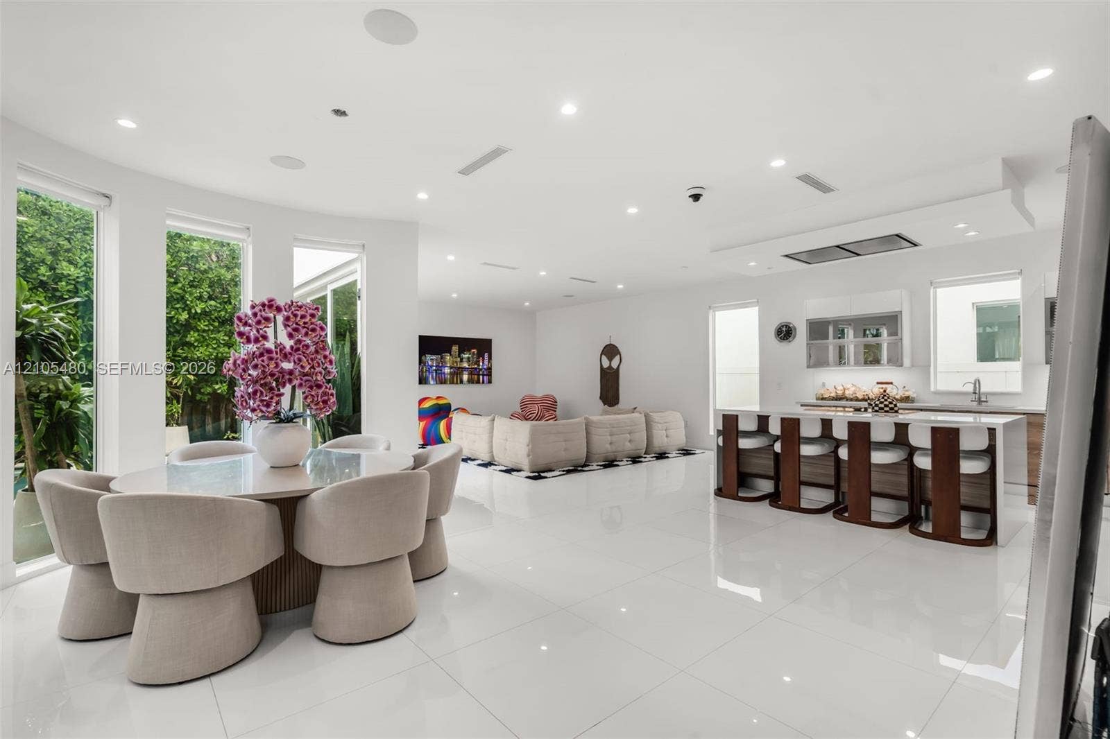 Spacious open-concept interior with polished tile flooring, recessed lighting, a kitchen island with seating, and large windows