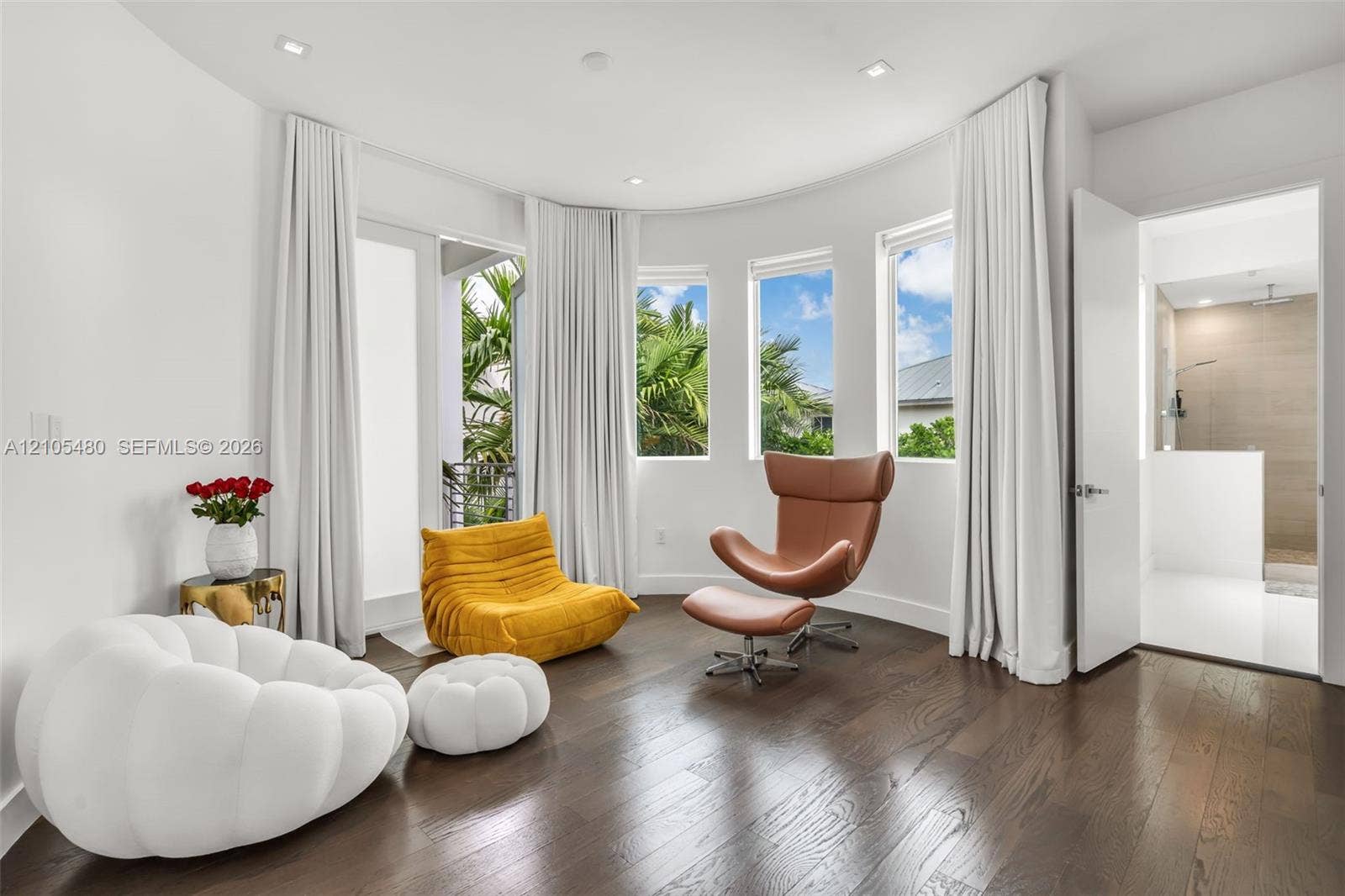 Curved wall with multiple windows, dark wood-finish flooring, recessed lighting, and a white interior door
