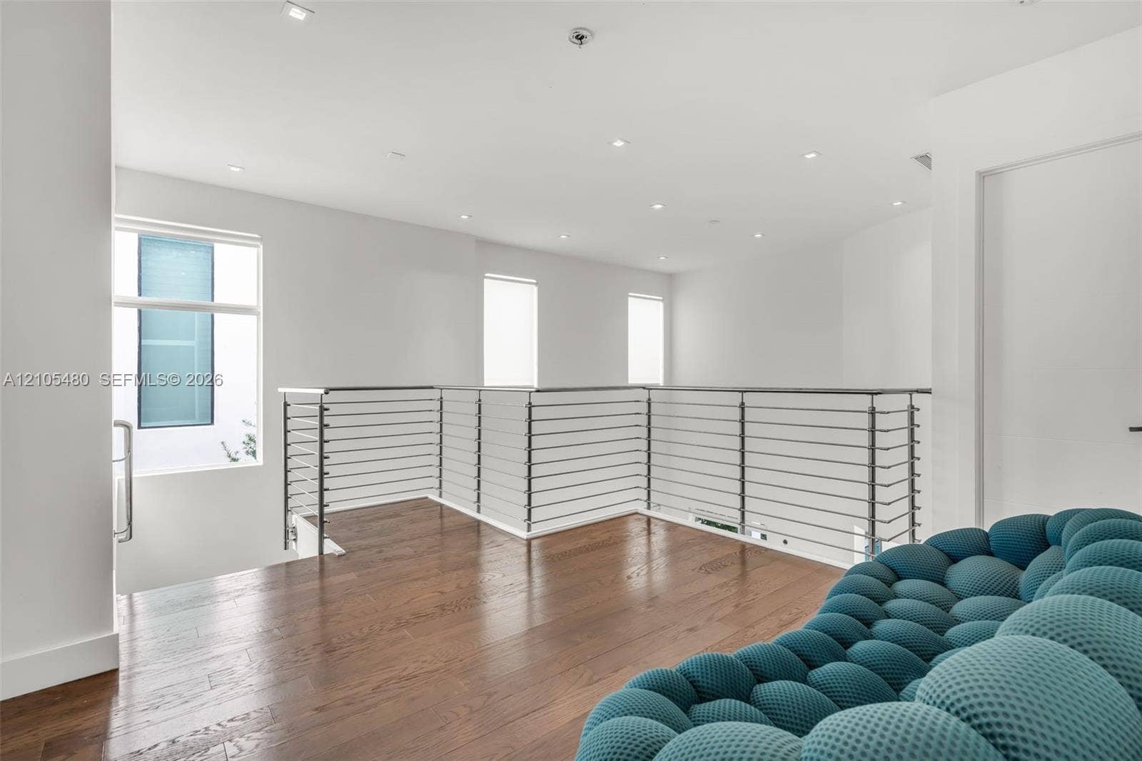 Hardwood flooring, contemporary cable railing, recessed lighting, white walls, and multiple windows