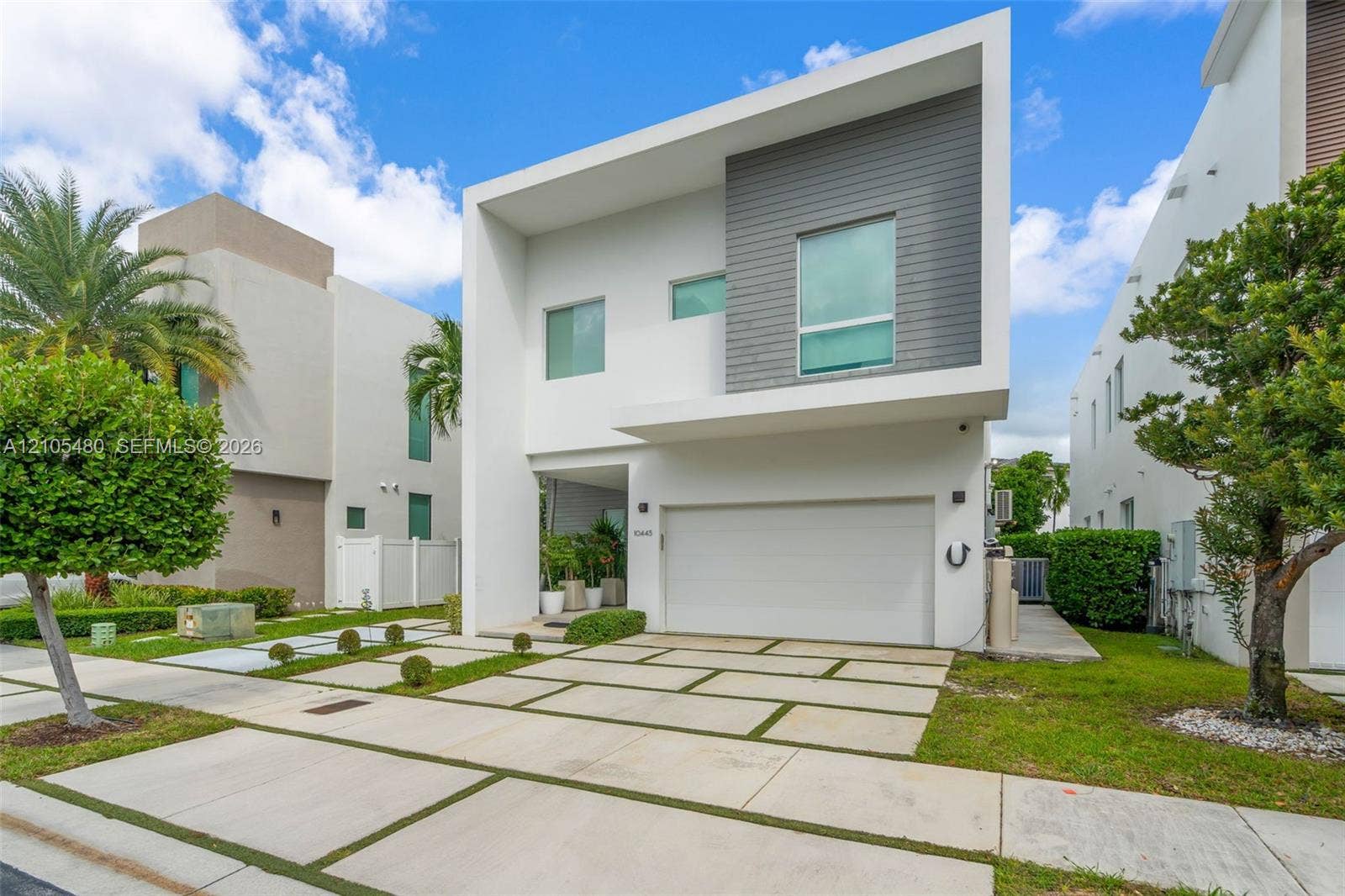 Modern two-story residence featuring a clean-lined architectural design with white exterior walls and horizontal gray metal accents