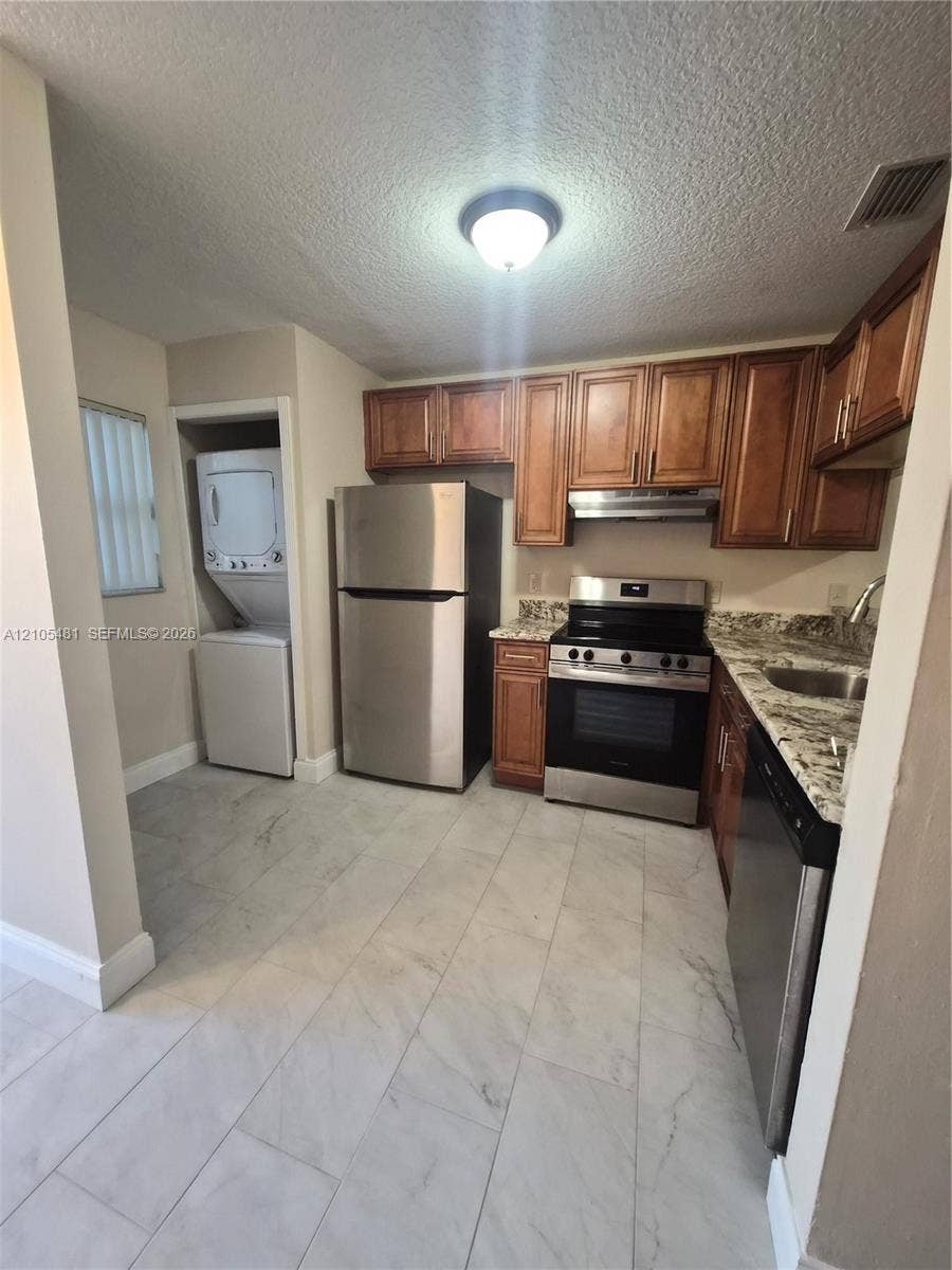 10909 Royal Palm Boulevard, #10909, Coral Springs, Coral Springs, FL 33065 Kitchen featuring wood cabinetry, stainless steel appliances, and stone-finish countertops