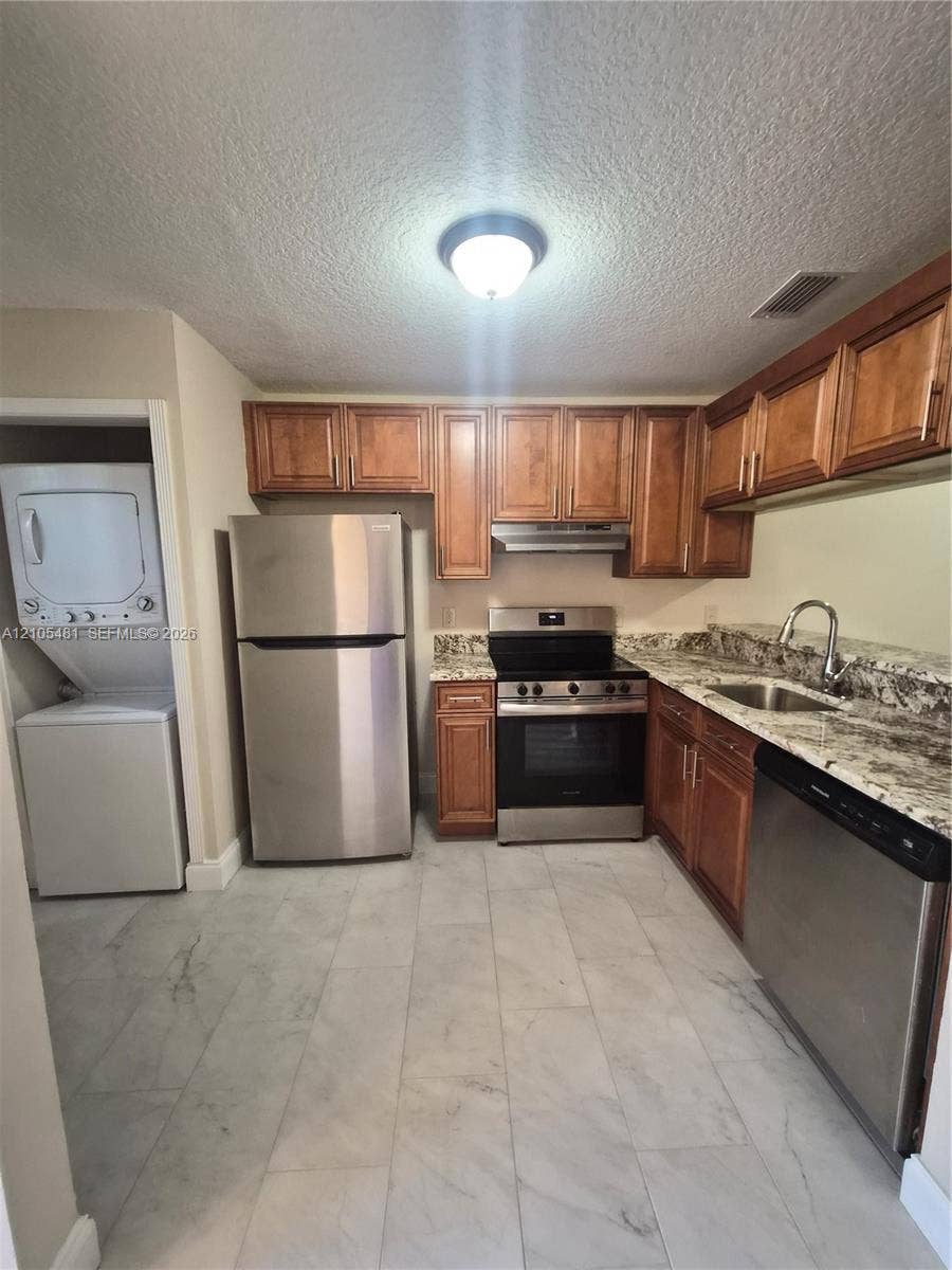 10909 Royal Palm Boulevard, #10909, Coral Springs, Coral Springs, FL 33065 Kitchen featuring wood cabinetry, light-toned stone countertops, stainless steel appliances, and large format tile flooring