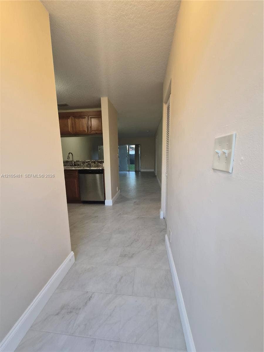 10909 Royal Palm Boulevard, #10909, Coral Springs, Coral Springs, FL 33065 Travertine-style floor tiling, light-colored wall paint, wood-finish cabinetry, stainless steel appliances, and a dark stone countertop