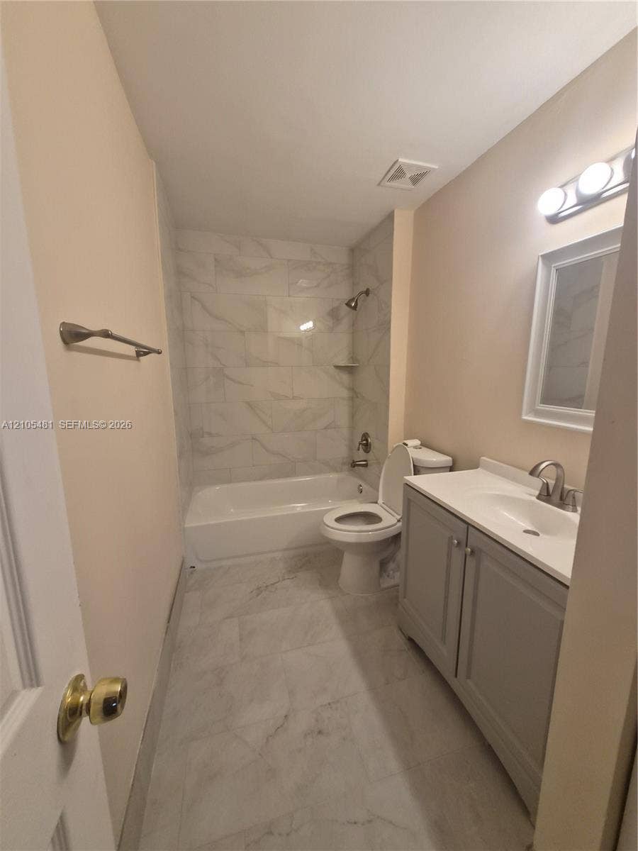 10909 Royal Palm Boulevard, #10909, Coral Springs, Coral Springs, FL 33065 White tiled shower with built-in shelf, white bathtub, gray vanity with white countertop, and light-toned walls