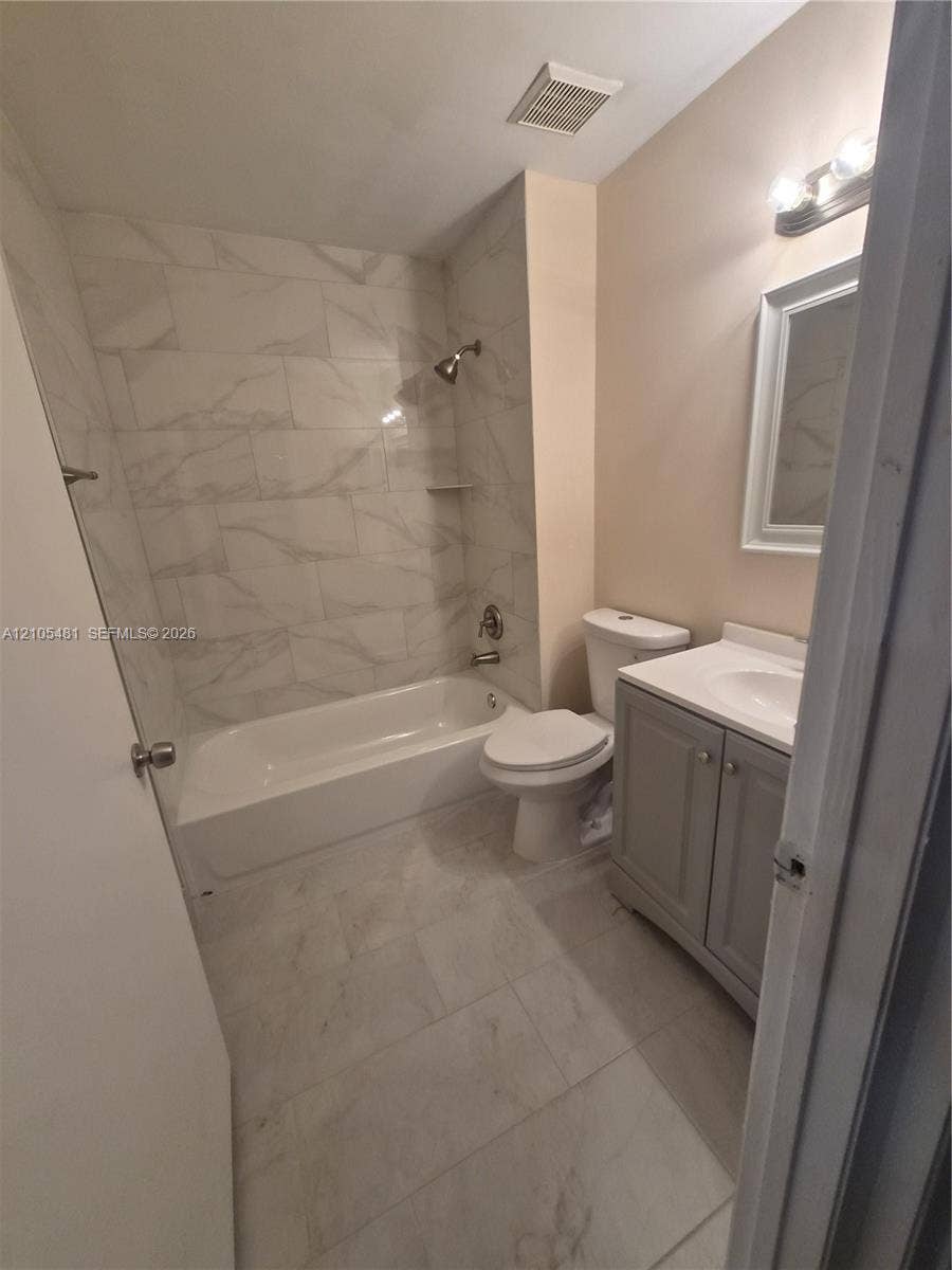 10909 Royal Palm Boulevard, #10909, Coral Springs, Coral Springs, FL 33065 White tile flooring, white tile tub surround, white bathtub, vanity with a white sink, and a rectangular mirror