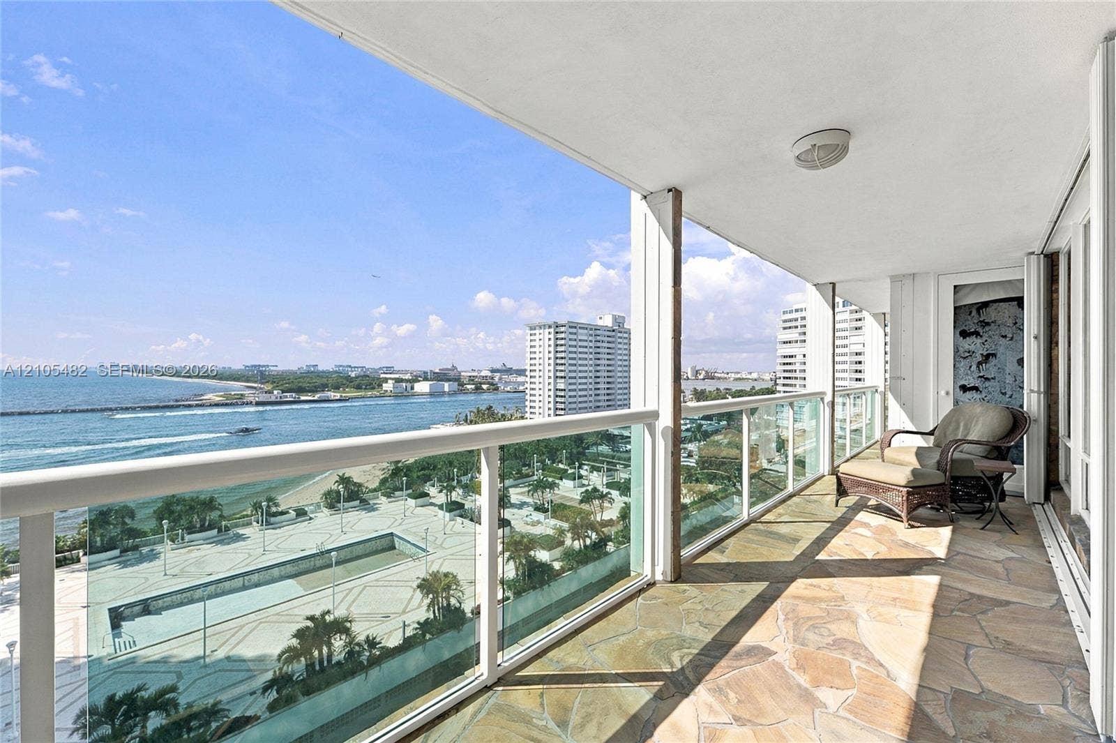 2100 S Ocean Lane, #808, Fort Lauderdale, FL 33316 Covered balcony featuring flagstone flooring, glass panel railings, and expansive ocean and coastal vistas