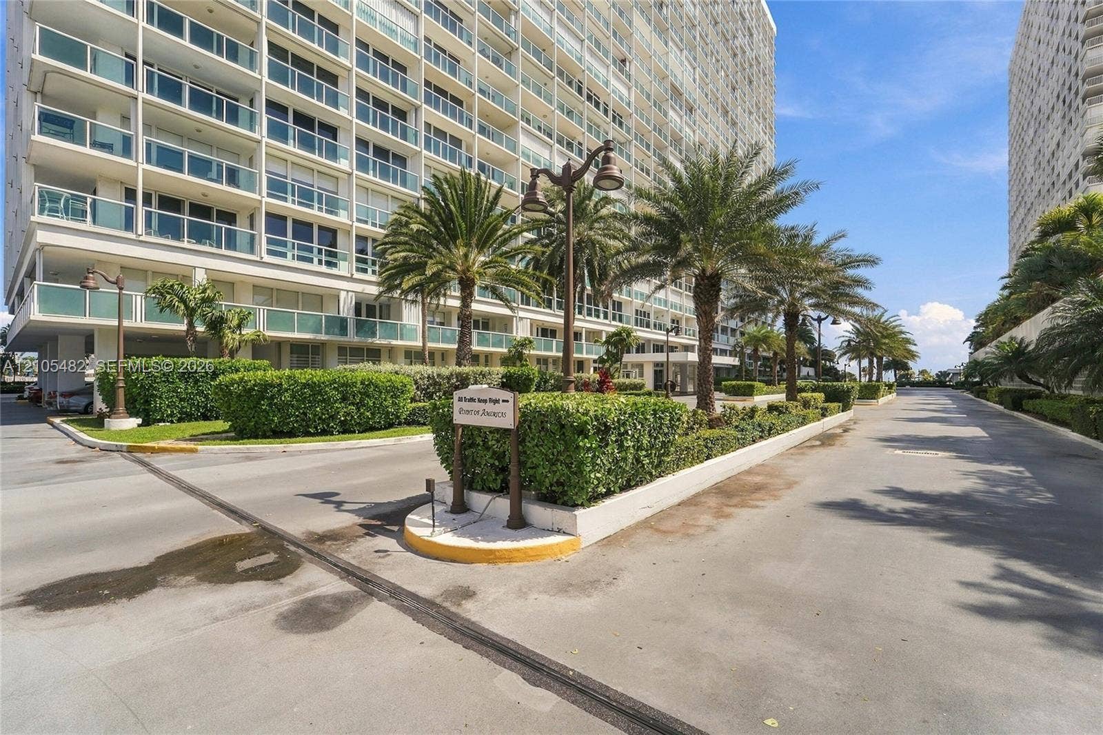 2100 S Ocean Lane, #808, Fort Lauderdale, FL 33316 High-rise exterior featuring private balconies with glass railings, landscaped grounds, mature palm trees, and asphalt driveways