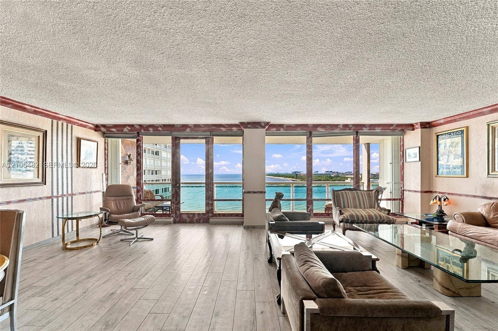 2100 S Ocean Lane, #808, Fort Lauderdale, FL 33316 Expansive floor-to-ceiling windows, wood-finish flooring, and built-in wall trim details featuring decorative stone-finish accents