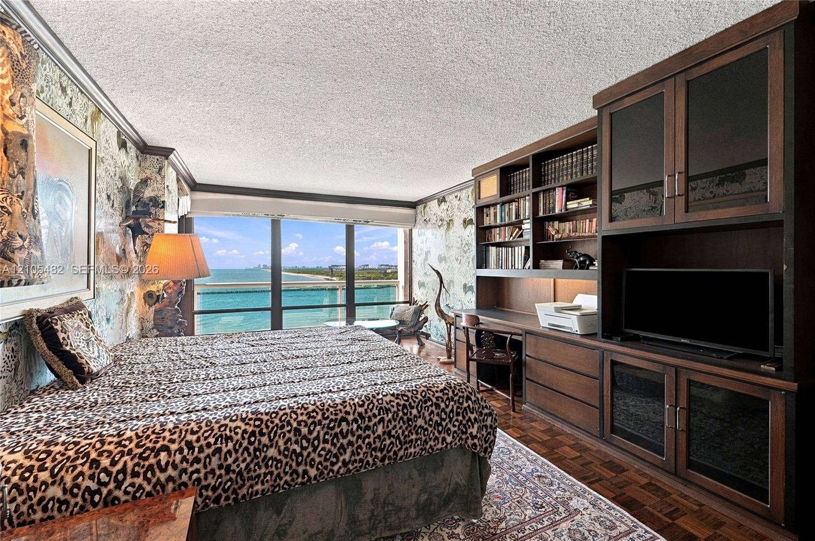 2100 S Ocean Lane, #808, Fort Lauderdale, FL 33316 Floor-to-ceiling windows with water backdrop, built-in dark wood cabinetry with integrated shelving and desk, and parquet wood flooring